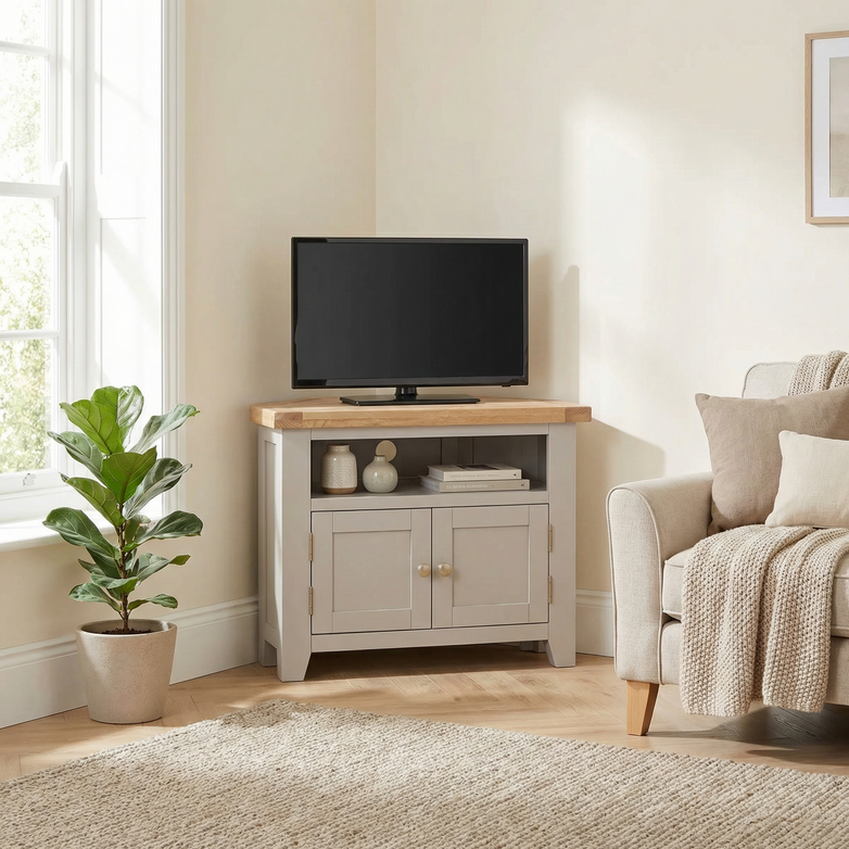 The Burford Corner Media Unit in Pebble Grey features a wooden top with rustic grain patterns, displaying a TV, decor, and cabinets.