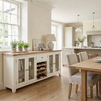 Bright, modern kitchen with wooden floors, potted plants, and the Burford Grand Sideboard with Wine Rack in Warm White, plus a dining table and chairs.