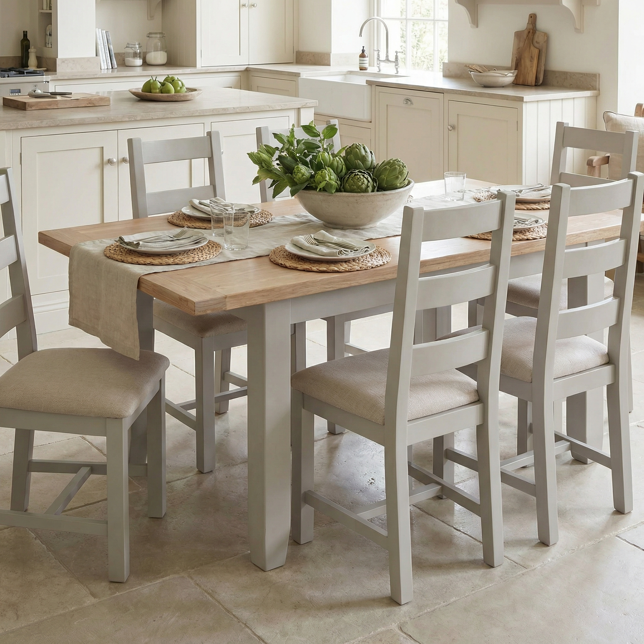 The Burford 6 Seat Extending Dining Set in Pebble Grey brightens the kitchen, set with plates and a bowl of artichokes.