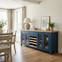 A Burford Grand Sideboard with Wine Rack in Navy Blue stands in a bright dining room featuring wooden floors and cream-colored curtains, adding an elegant touch to the decor.
