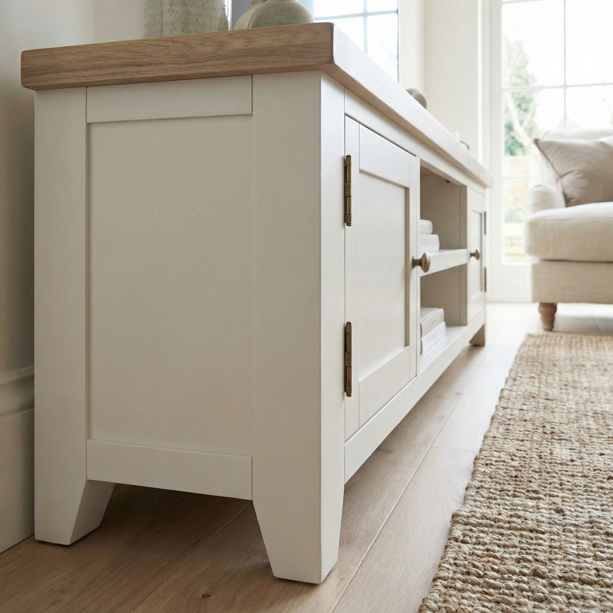 The Burford Large 180cm Media Unit in Warm White features spacious shelves and sits in a bright living room, perfectly paired with a cozy fabric dining chair for added comfort and style.