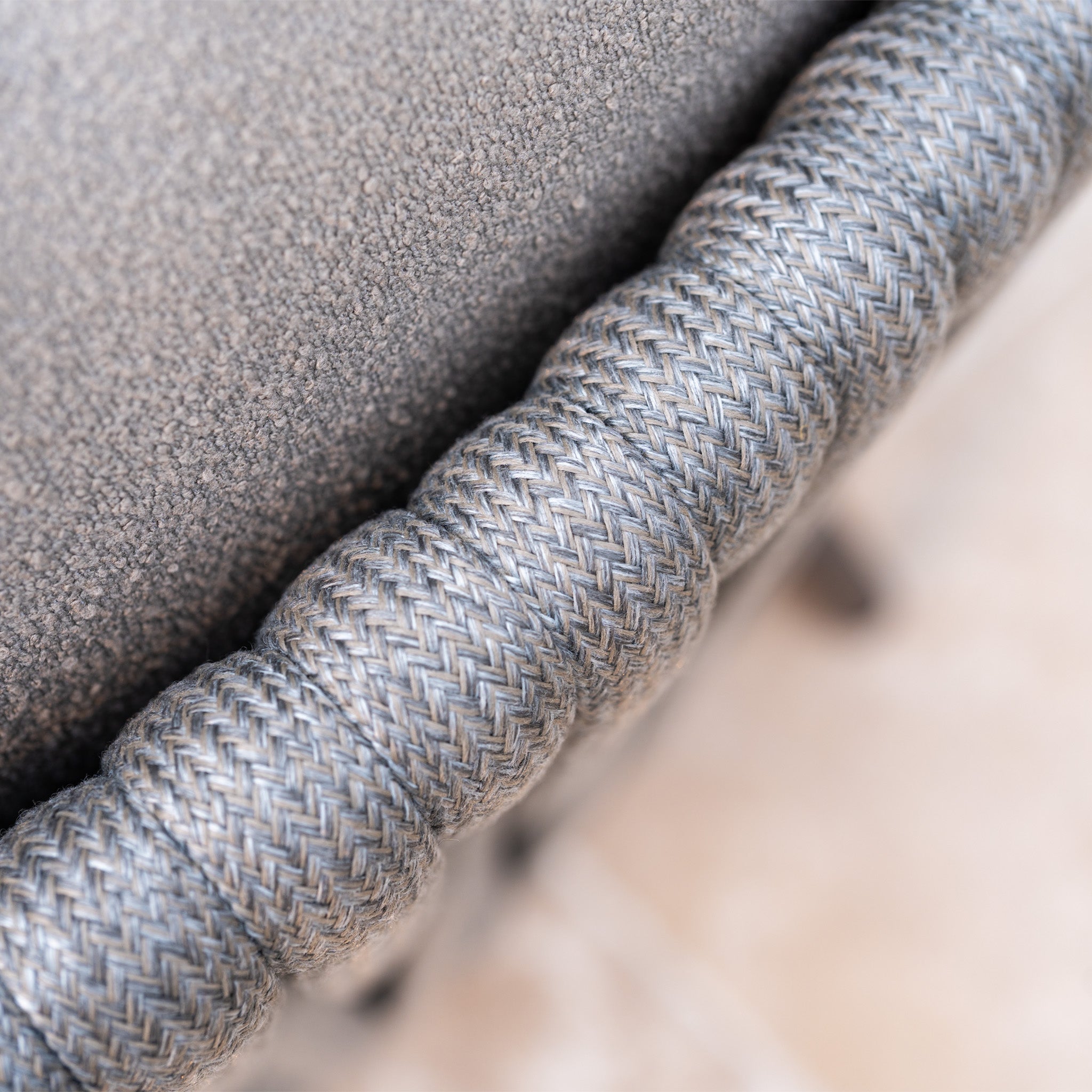 Close-up of a textured, braided gray rope attached to soft gray fabric—details from the Capri 4 Seat High Rectangular Dining Set in Stone Grey, a stylish outdoor dining set.