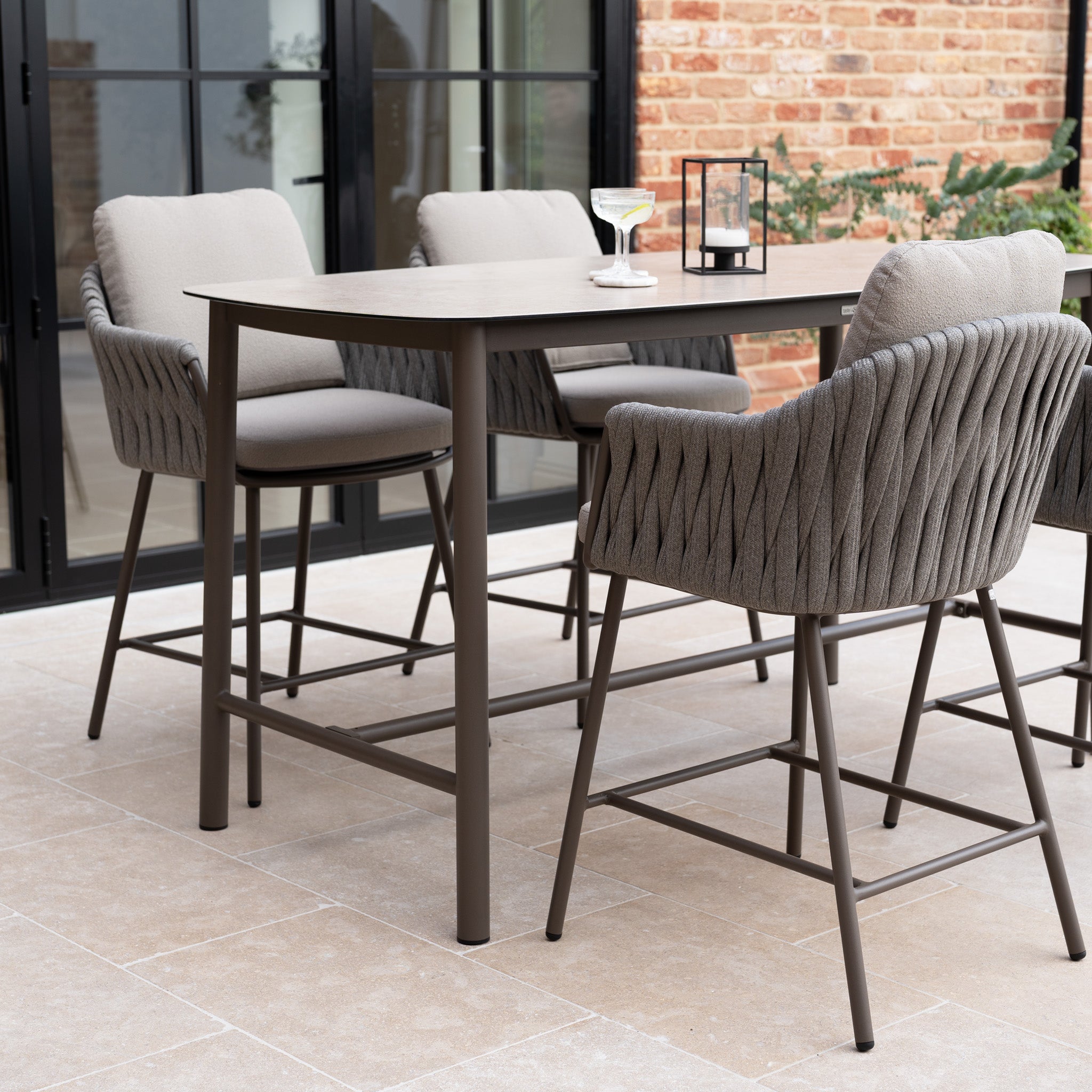 The Capri 4 Seat High Rectangular Dining Set in Stone Grey features four cushioned chairs and a tall table, perfect for creating an inviting dining space on your patio.