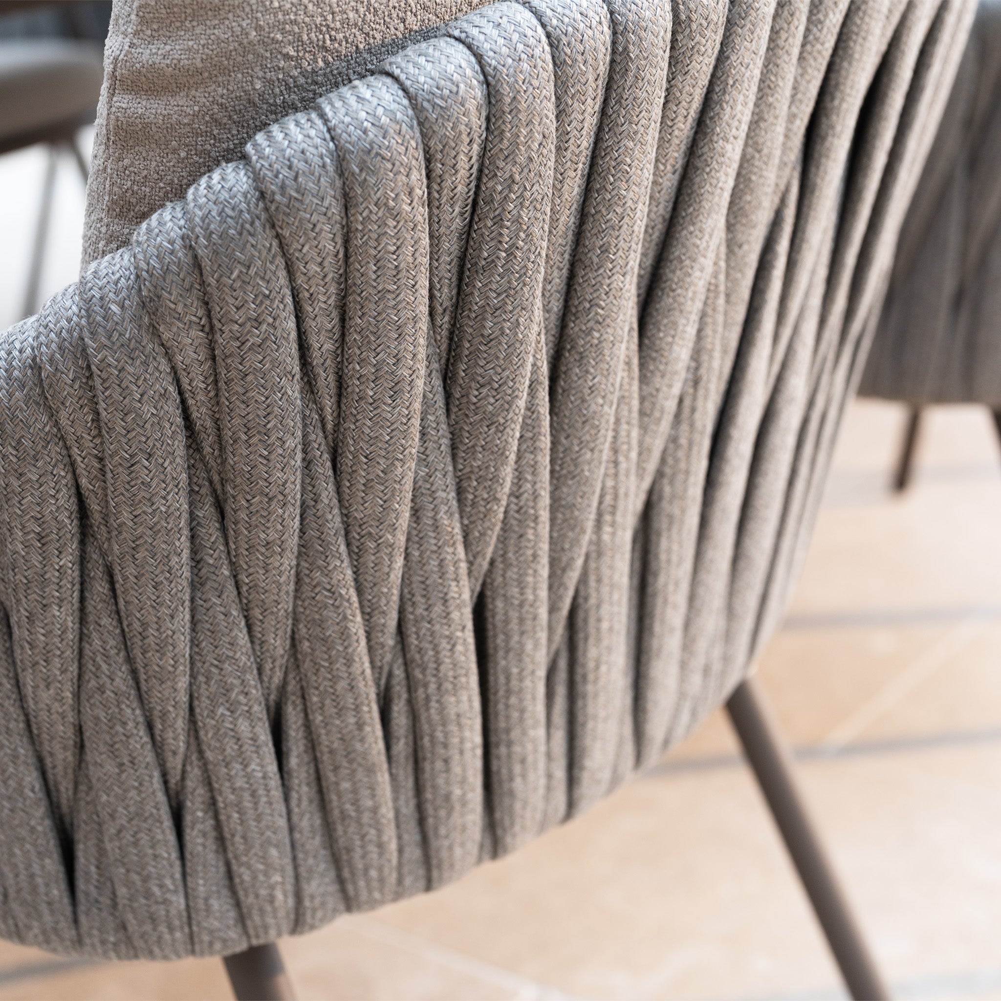 Close-up of a modern chair from the Capri 8 Seat Curved Rectangular Dining Set in Stone Grey, featuring textured woven gray upholstery and brown metal legs—a stylish choice for any stone grey outdoor setting.