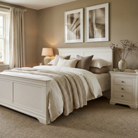 Cozy bedroom featuring the Chalbury 5ft High-End Kingsize Bed Frame in warm white, neutral bedding, two framed artworks, plus a nightstand with a lamp and vase.