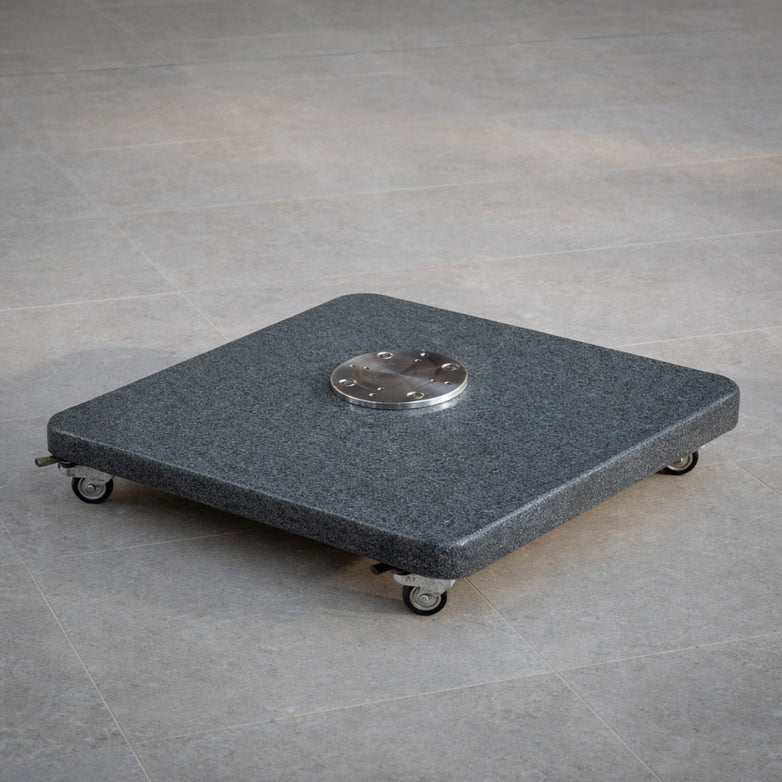 The Granite 120kg Cantilever Parasol Base With Wheels, topped with a metal plate, rests securely on a tiled floor.