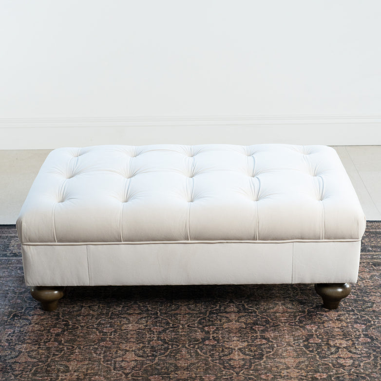The Chesterfield Velvet Footstool in Cream features a rectangular tufted design with wooden legs—an elegant accent piece or ottoman for bright rooms.