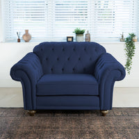 The Chesterfield Velvet Loveseat in Royal Blue graces the bright room with white blinds, its elegance accentuated by decor on the windowsill. Handmade in the UK, this piece adds sophistication to any setting.