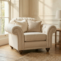 Chesterfield Armchair in Ivory with two pillows beside a window in a cozy, sunlit room with wooden floors.