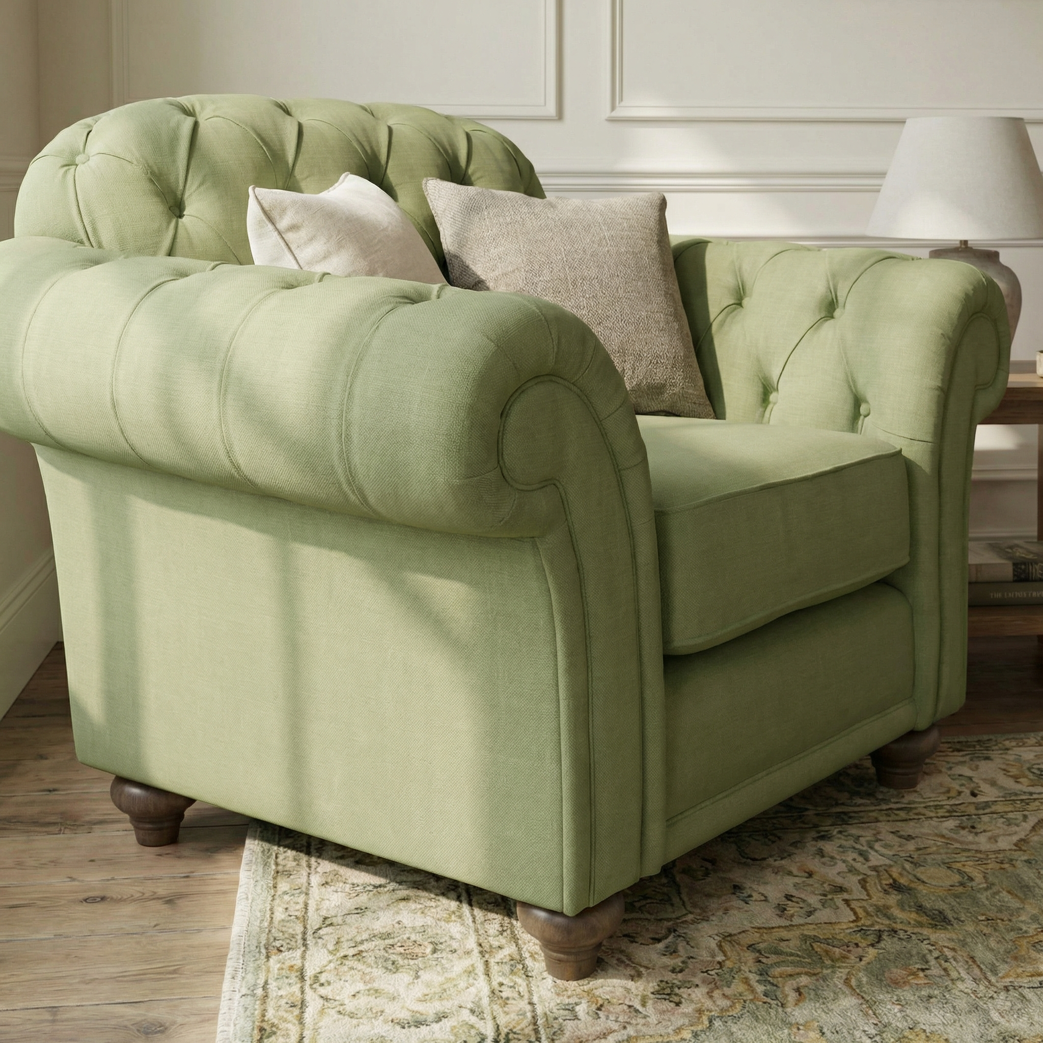 The Chesterfield Armchair in Olive, handcrafted in England with classic British design, is accented with neutral throw pillows and sits on a patterned rug in a cozy, sunlit room.