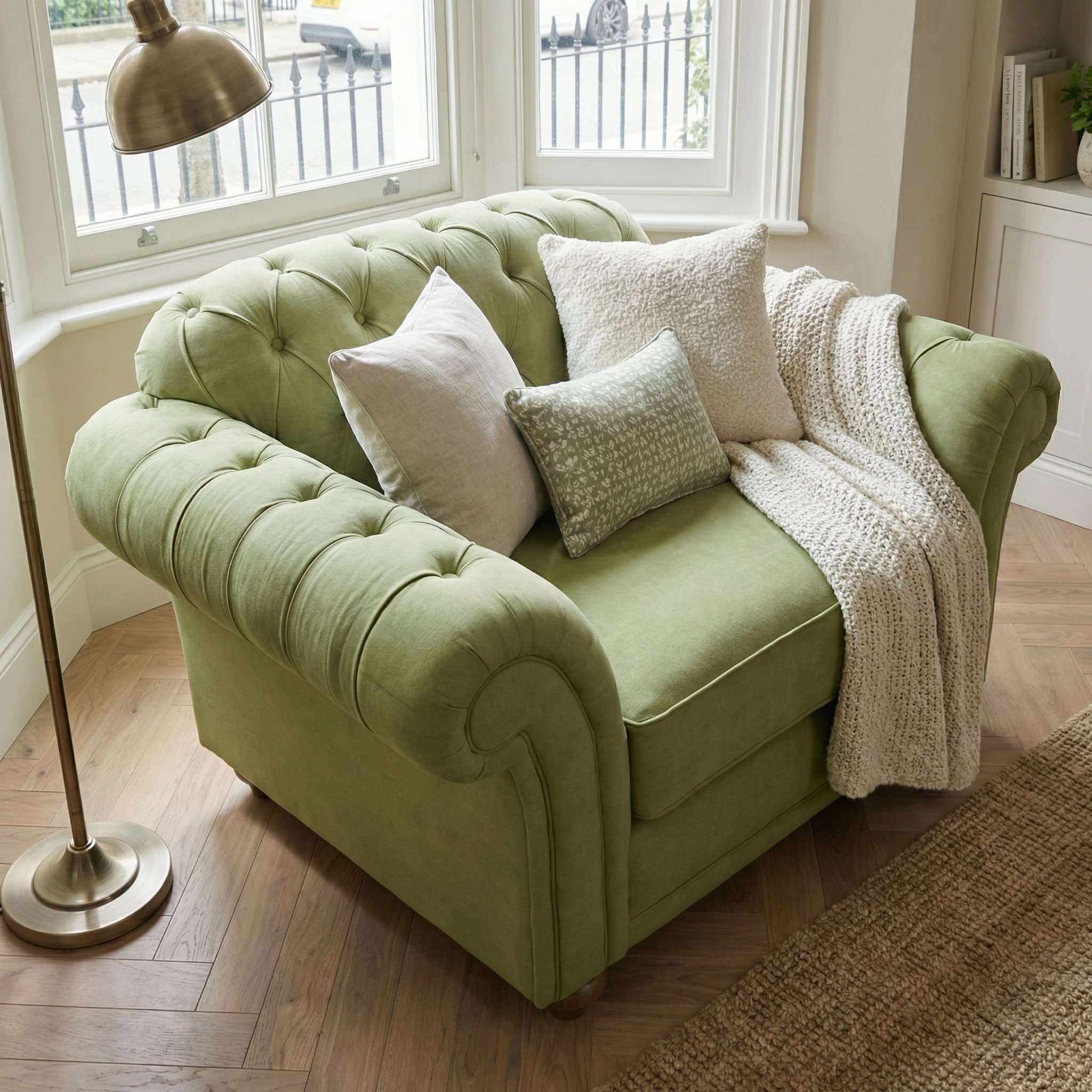 Olive Chesterfield Loveseat with white pillows and a textured blanket in a cozy, sunlit living room.