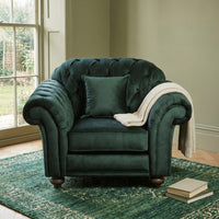 Chesterfield Velvet Armchair in Bottle Green with cushion and blanket, set on a green rug by the window, books scattered nearby.