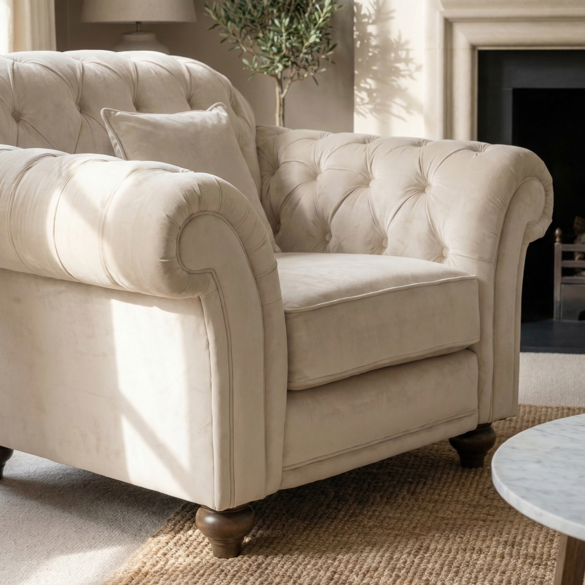 Chesterfield Velvet Armchair in Cream with cushion, set on a woven rug in a bright, cozy living room—an inviting and sustainable furniture choice.