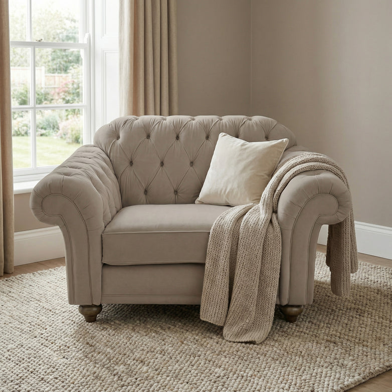 Beige armchair with cushion and knitted throw, paired with the Chesterfield Velvet Loveseat in Mink, in a bright room featuring a large window and neutral decor.