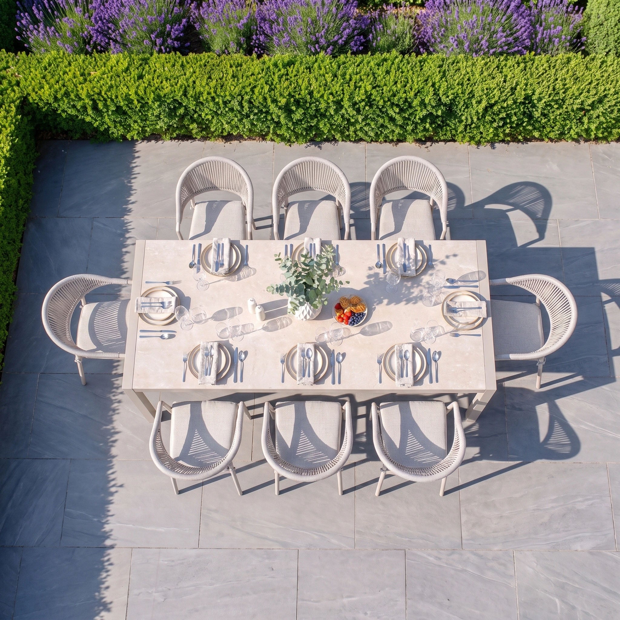 Experience outdoor dining at its finest with the Cloverly 8 Seat Dining Set, featuring the sophisticated Ravona Extending Table in Latte and inviting patio chairs. The beautifully set table is surrounded by ample seating and topped with floral accents and a fruit bowl, cultivating a warm, welcoming atmosphere on your garden patio.