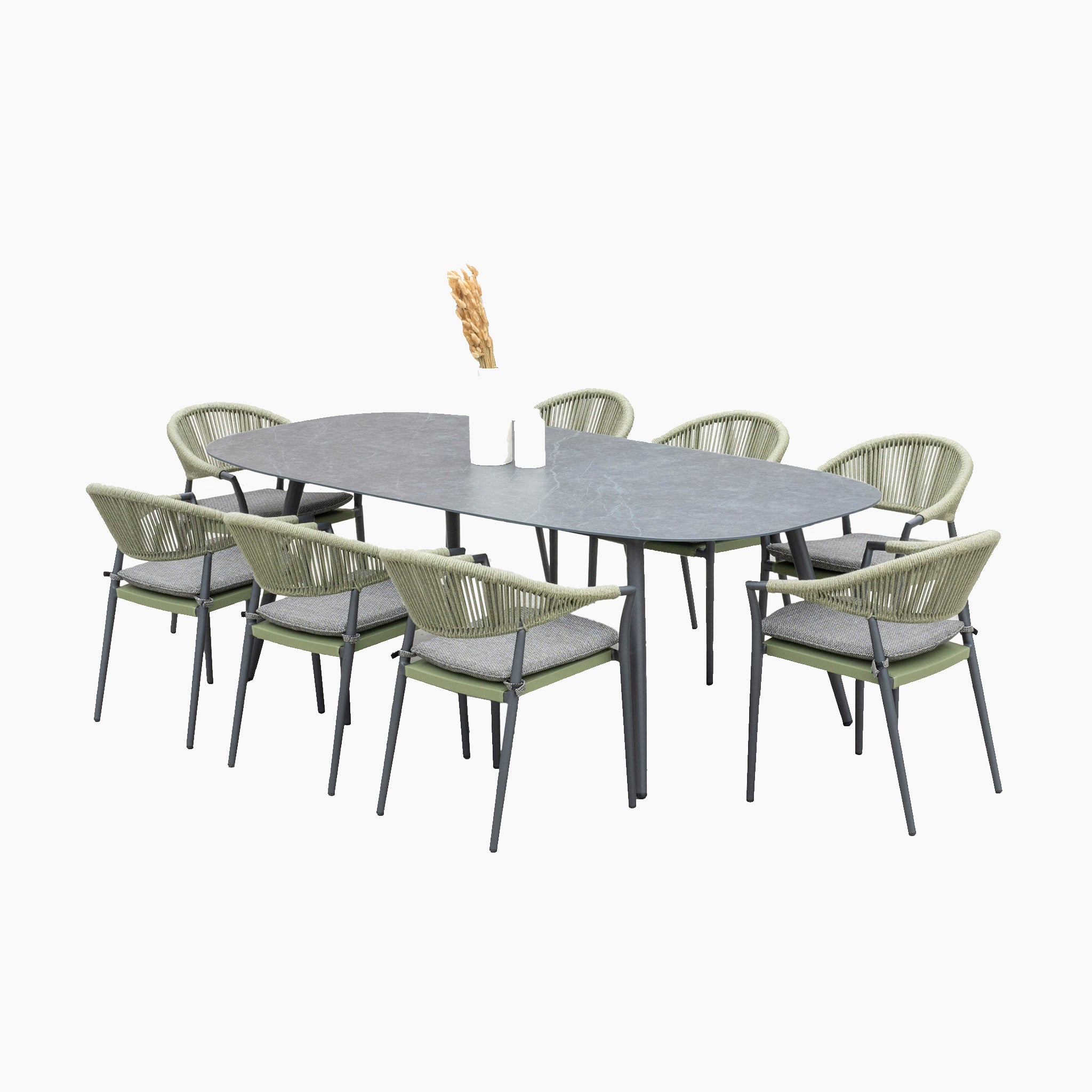 A Cloverly 8 Seat Rope Oval Dining Set with a Ceramic Table in Olive Green features a modern dining table surrounded by six stackable woven chairs, with a vase of dried wheat stalks at its center.
