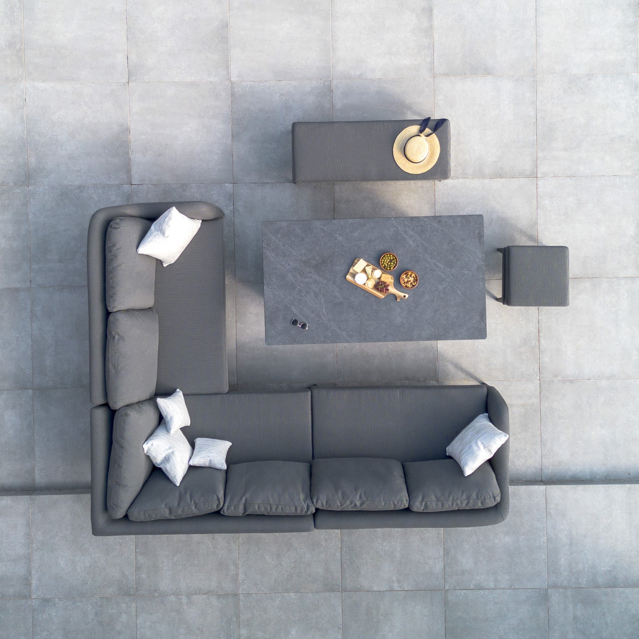 Top view of the Luna Outdoor Fabric Rectangular Corner Dining Set with Rising Table in Grey (Right Hand) by Harbour Lifestyle, featuring a grey L-shaped couch, table, and stools on a tiled patio.