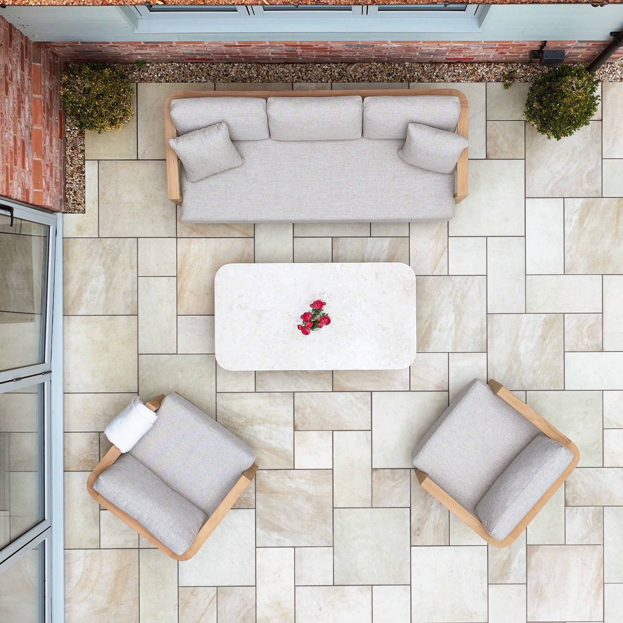 Patio with a Tivoli 3 Seat Sofa Set with Marble Coffee Table in Fawn, plus two armchairs and a small flower arrangement, seen from above.