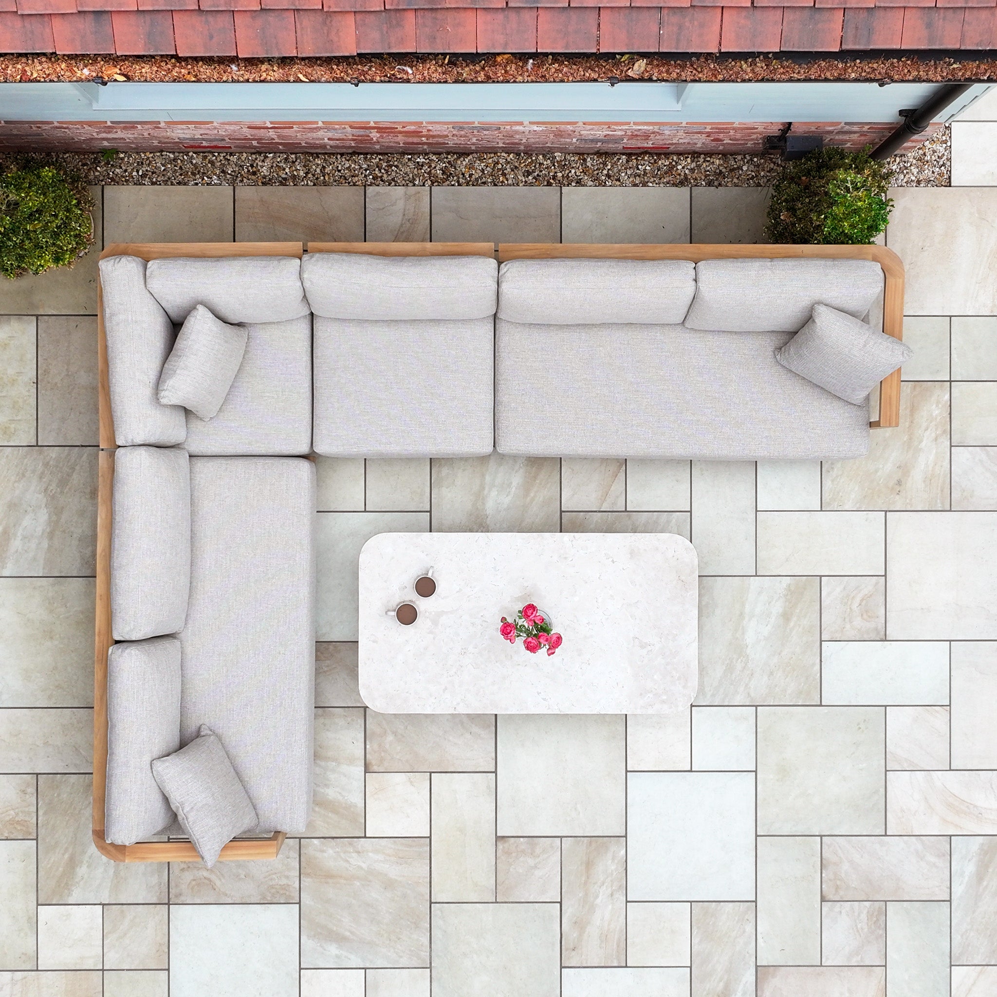 Overhead view of a Tivoli Large Corner Set with Marble Coffee Table in Fawn on a tiled patio, complete with cushions and two plants.