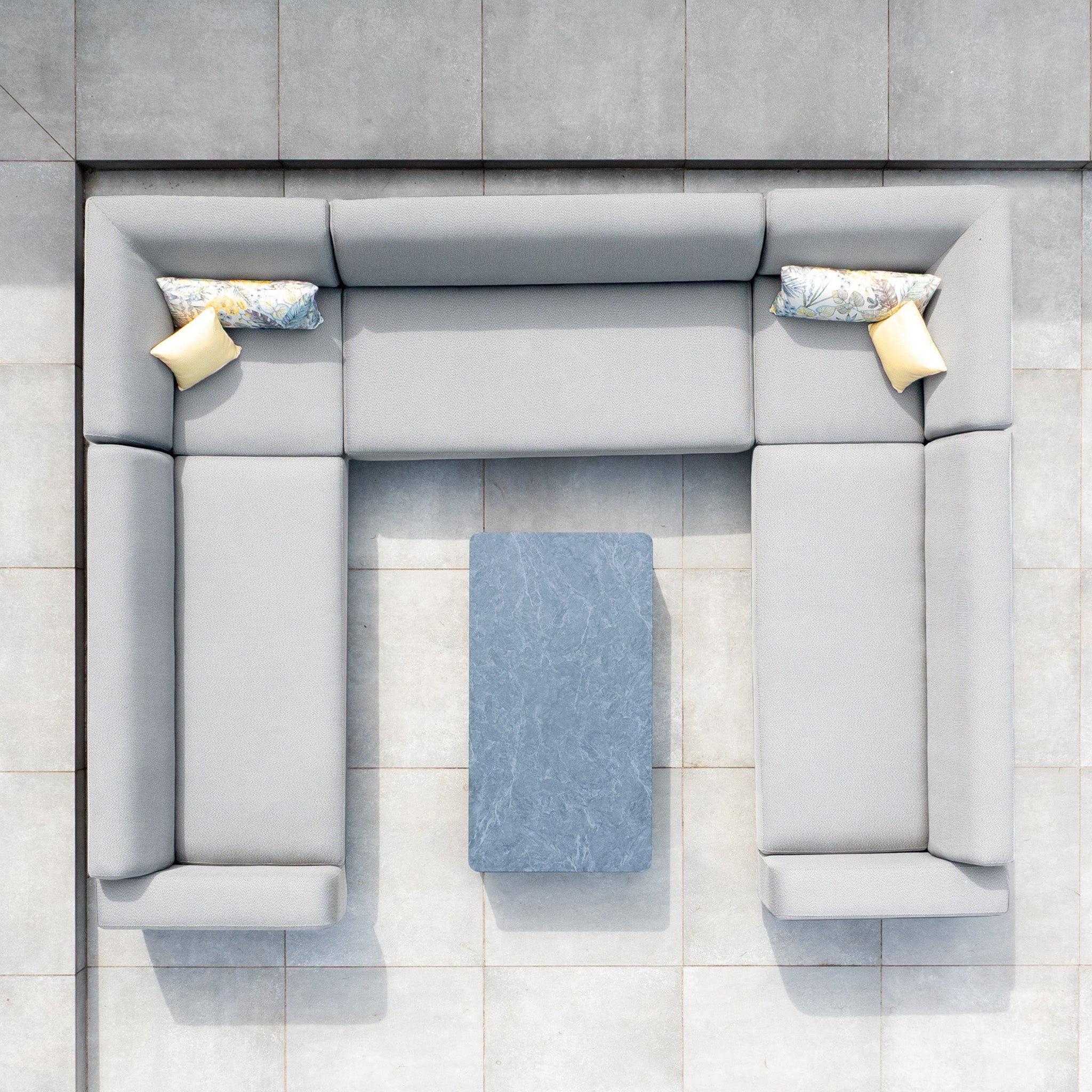 Top view of the Luna U-Shape Outdoor Fabric Sofa Set with Coffee Table in Oyster Grey, featuring two pillows and a rectangular table on a tiled floor.