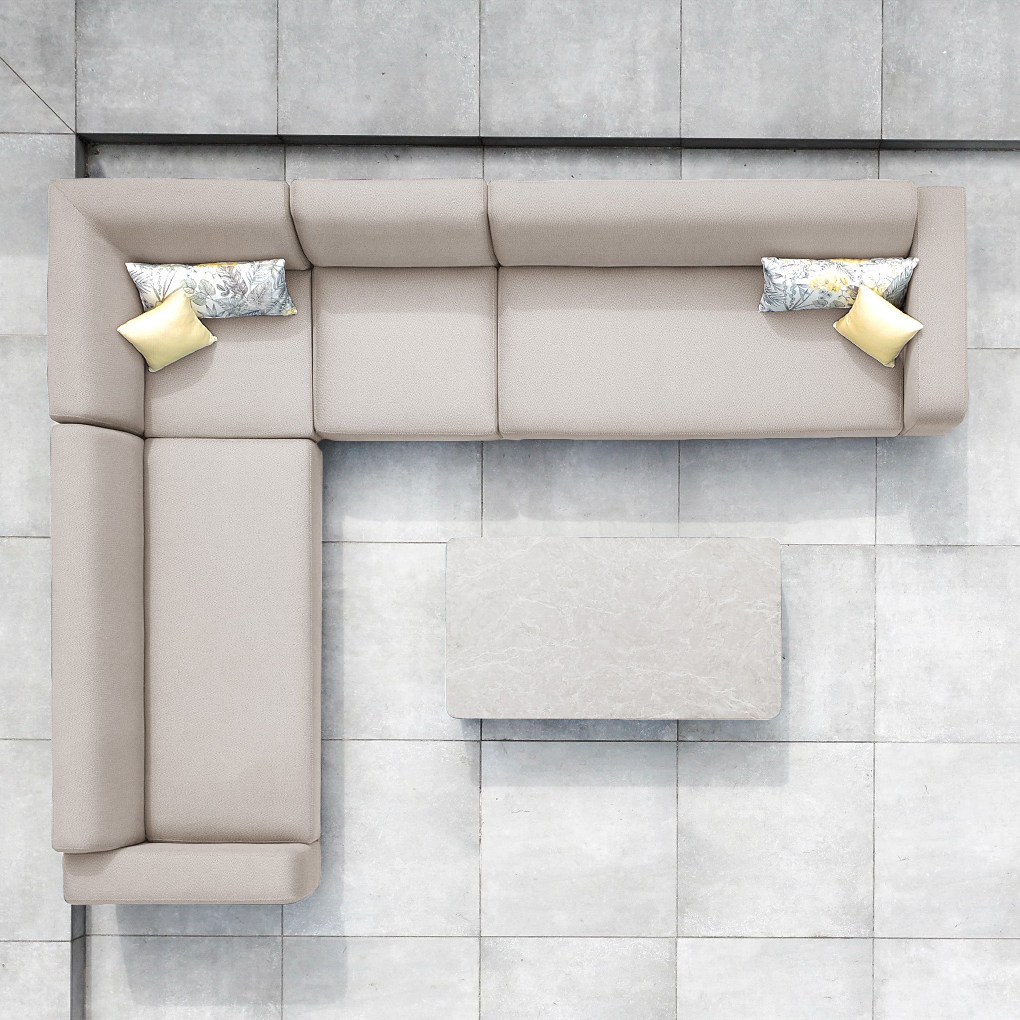 Top view of the Luna Outdoor Fabric Large Corner Group Set with Coffee Table in Fawn, an L-shaped beige sofa with four pillows on gray tiles, crafted from durable all-weather materials.