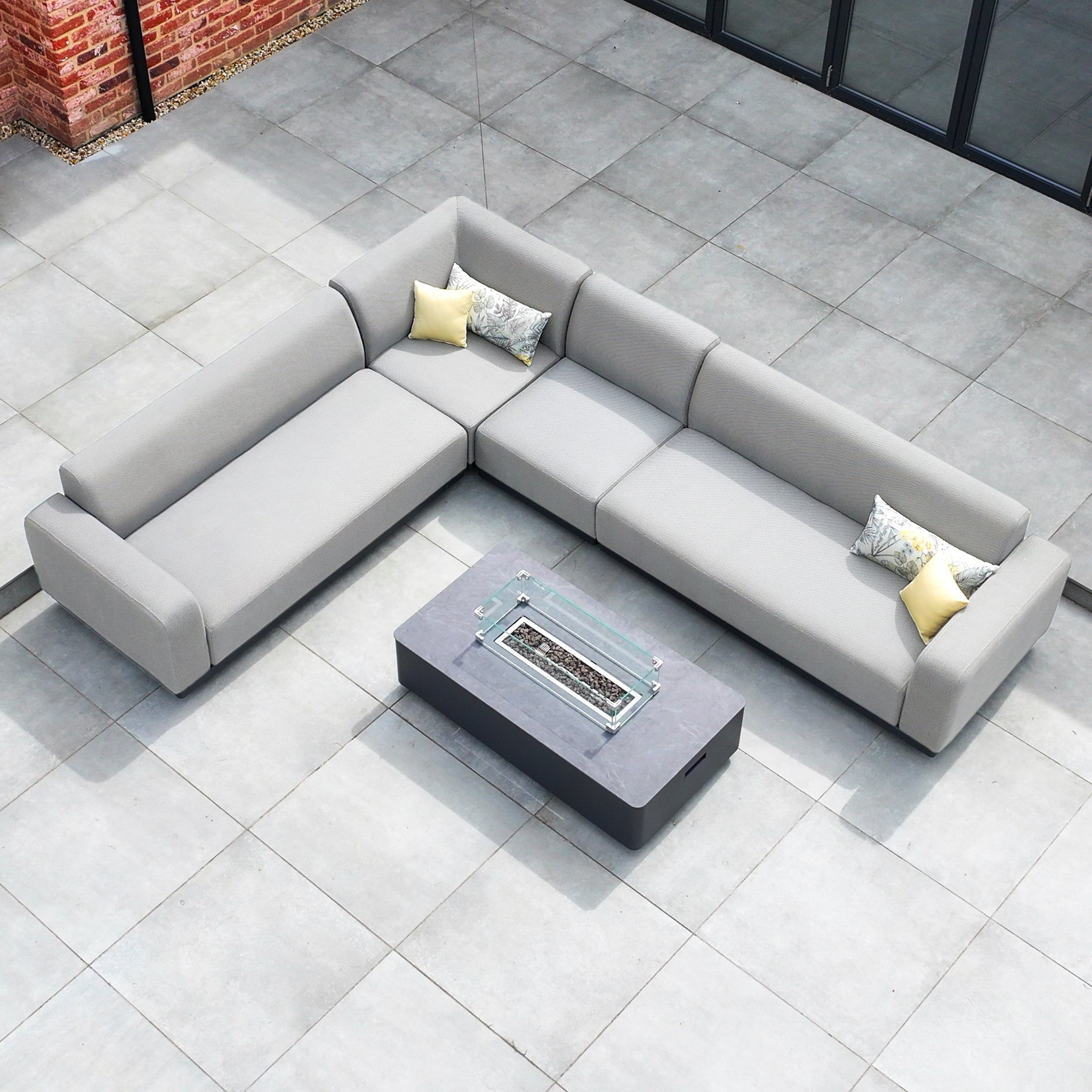 The Luna Outdoor Fabric Large Corner Group Set with Firepit Coffee Table in Oyster Grey sits on a tiled patio.