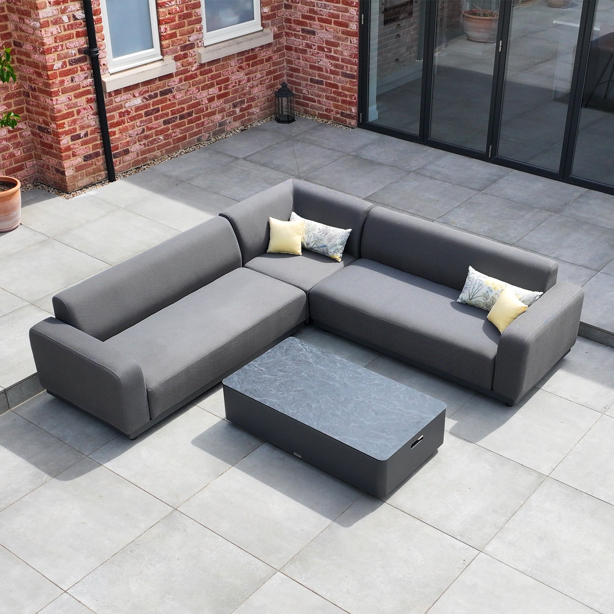 The Luna Outdoor Fabric Corner Sofa Set with Coffee Table in Grey features an L-shaped, all-weather design with stain-proof cushions, perfect for your tiled patio.