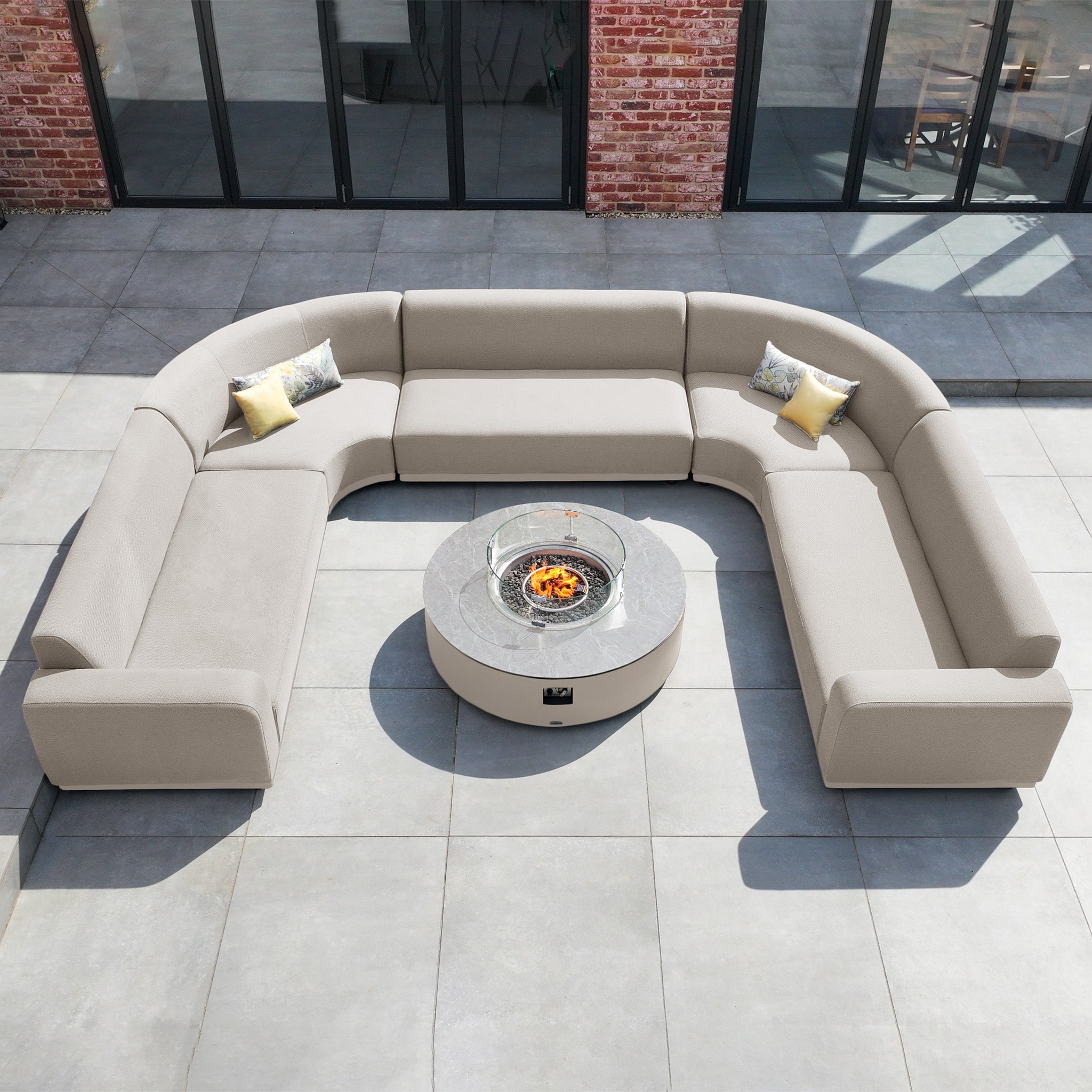 The Luna U-Shape Outdoor Fabric Curved Corner Group with Round Firepit Coffee Table in Fawn creates an inviting outdoor living space, featuring plush seating and a cozy firepit centerpiece on your patio.