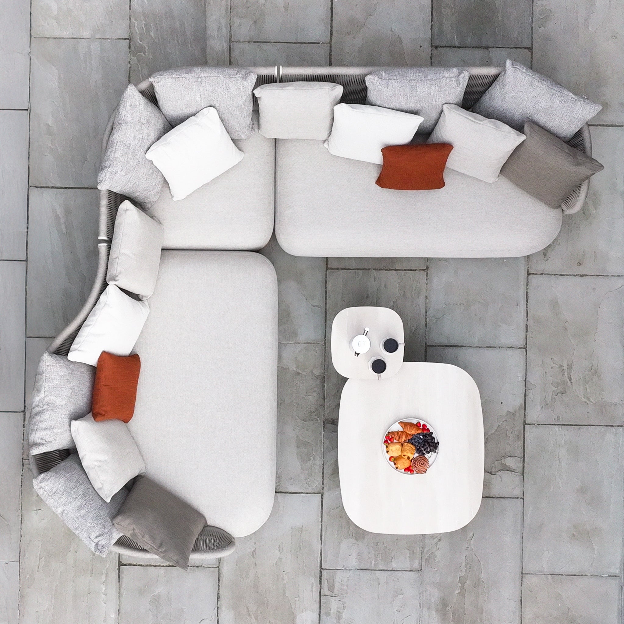 The Avola Deluxe Corner Sofa Set in Fawn (Right Hand) offers weather-resistant Olefin rope, fawn and grey cushions, a rust cushion, and a white coffee table—ideal for stylish outdoor relaxation.