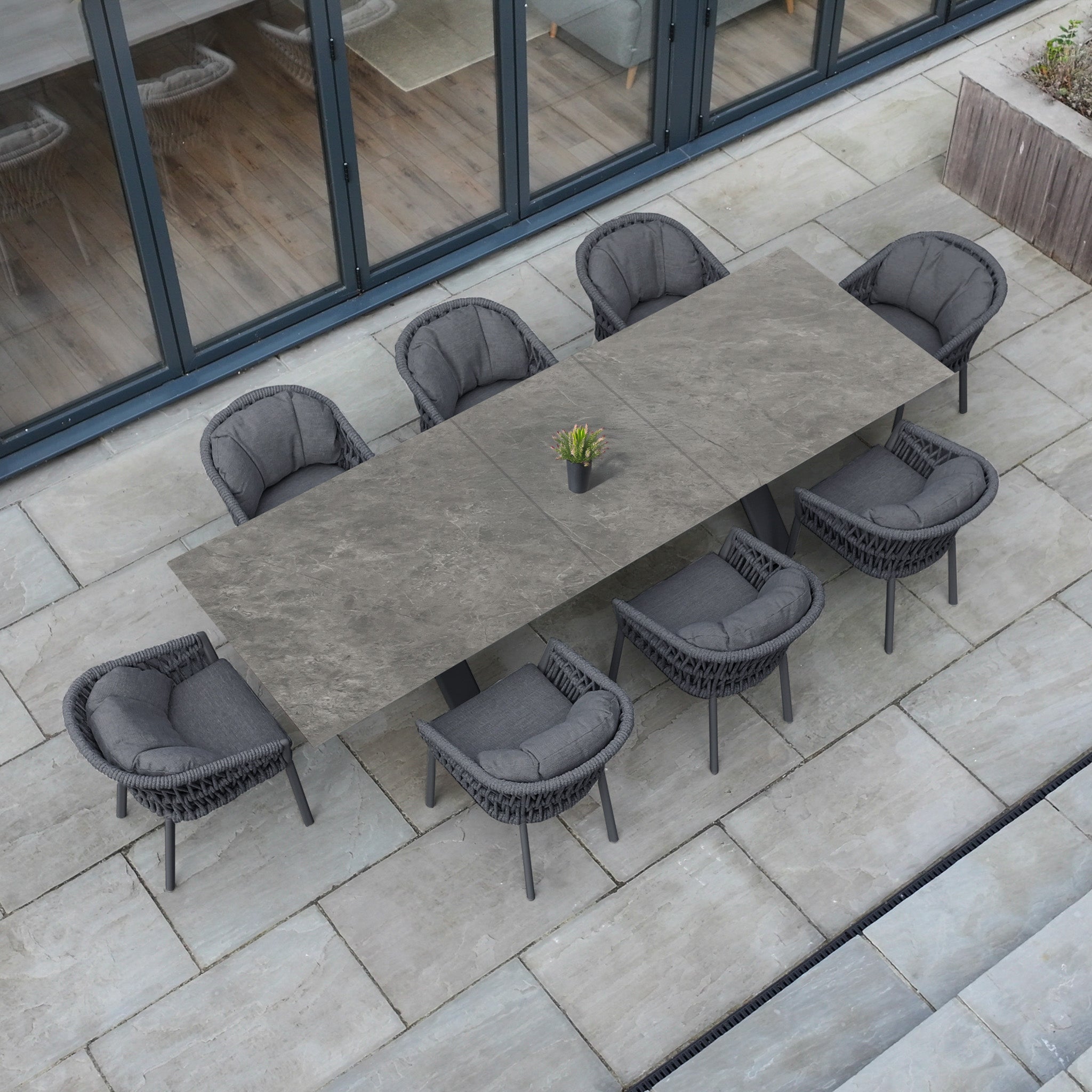 The Pello 8 Seat Dining Set with Albatross Extending Table in Grey features eight cushioned chairs and a stylish central plant, making it perfect modern garden furniture for gatherings on your patio.