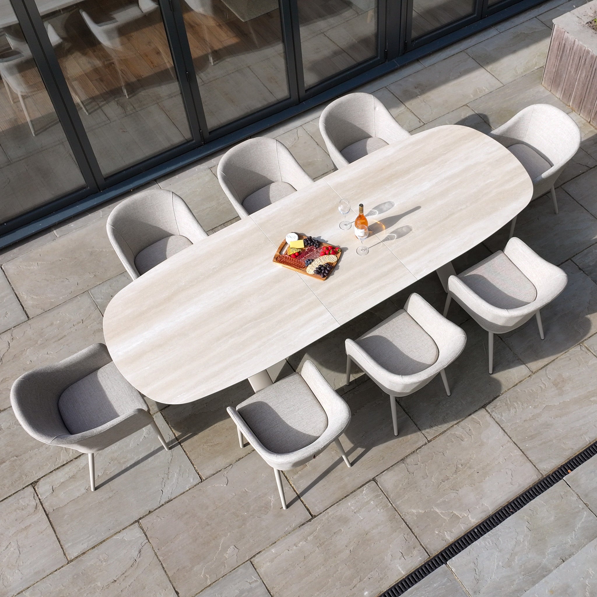 The Luna 8 Seat Outdoor Fabric Oval Dining Set with Albatross Extending Table in Fawn features UV resistant cushions for comfort and durability, perfect for outdoor gatherings on your patio next to glass doors.
