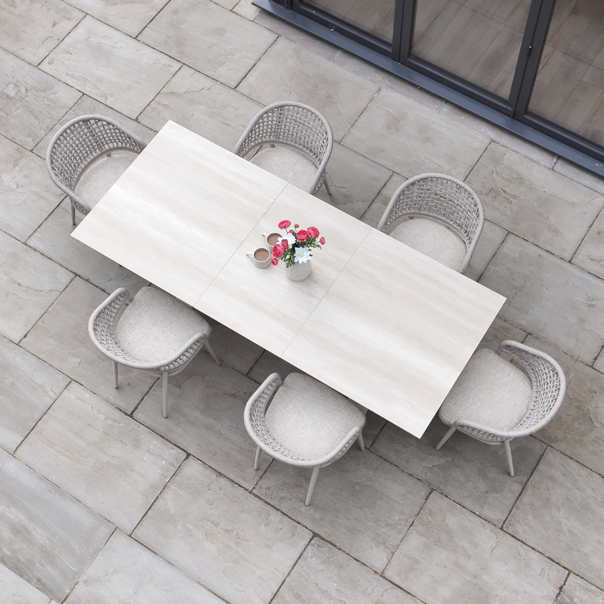 The Kalama 6 Seat Rope Dining Set with Albatross Extending Table in Oatmeal features a spacious outdoor table and six chairs, perfect for patios.