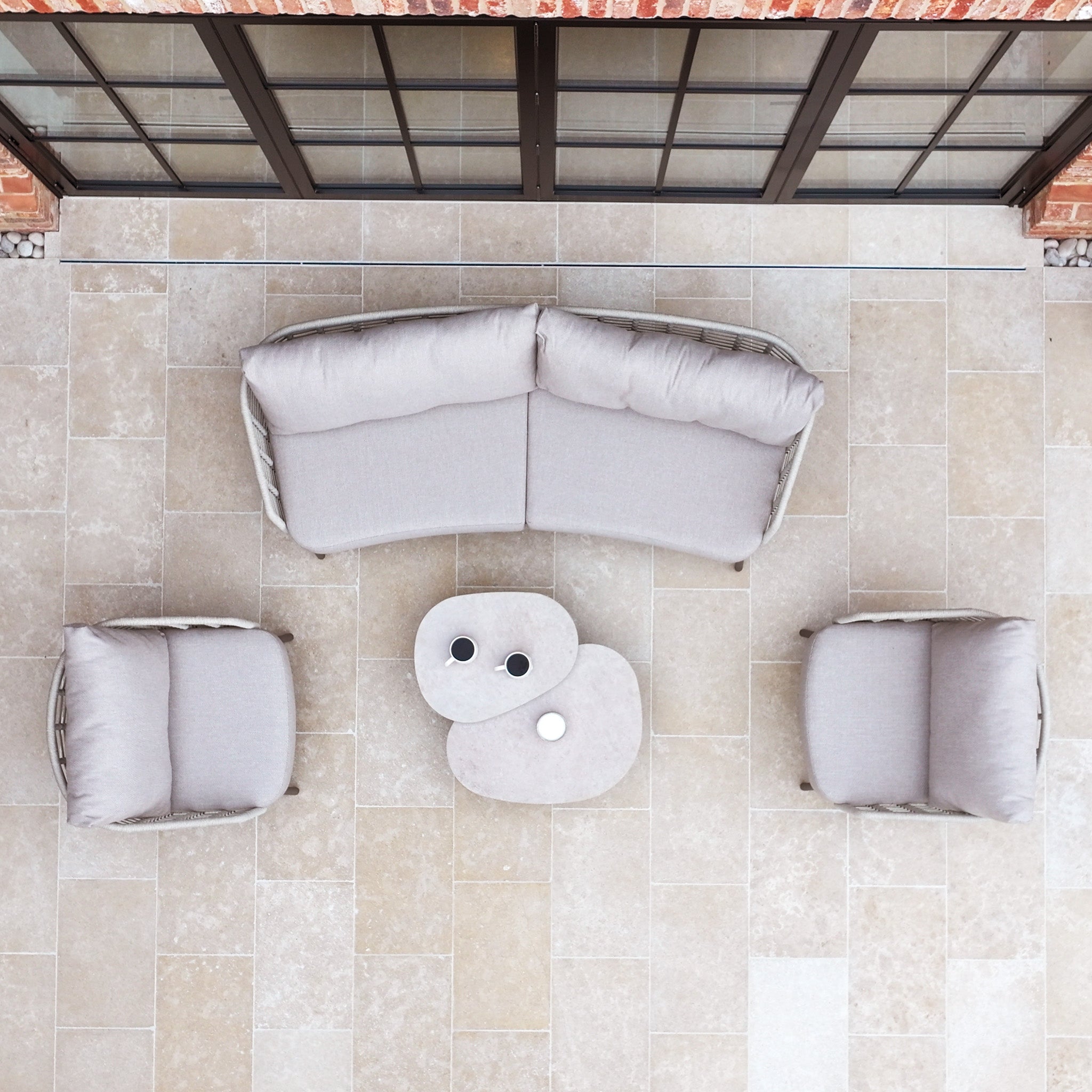 Aerial view of the Sutera 3 Seat Sofa Set in Putty with all-weather cushions, two chairs, and two small oval tables arranged on a tiled floor.