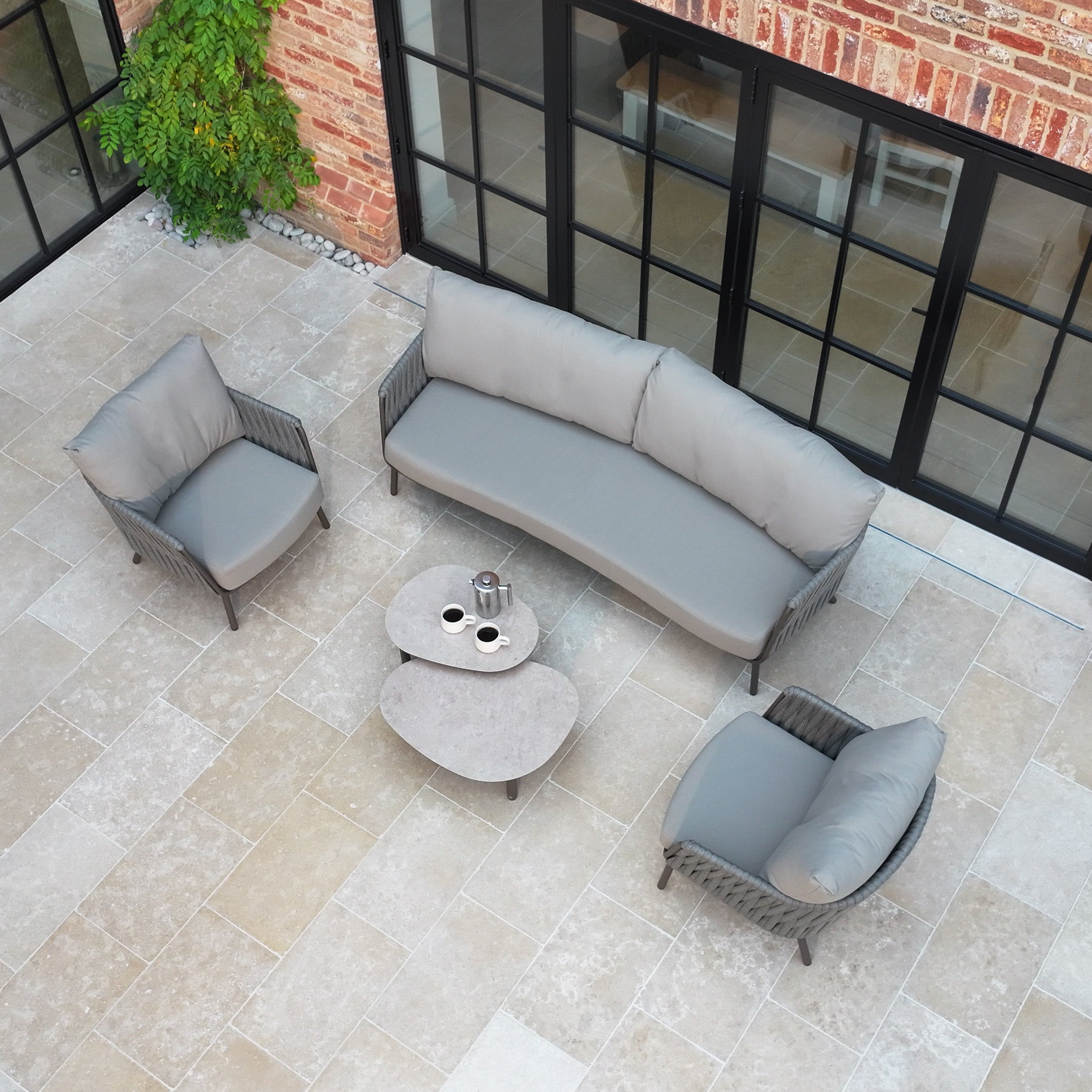 The Capri 3 Seat Sofa Set in Stone Grey includes a cushioned sofa, two chairs, and two nested coffee tables—stylish garden furniture ideal for any patio.