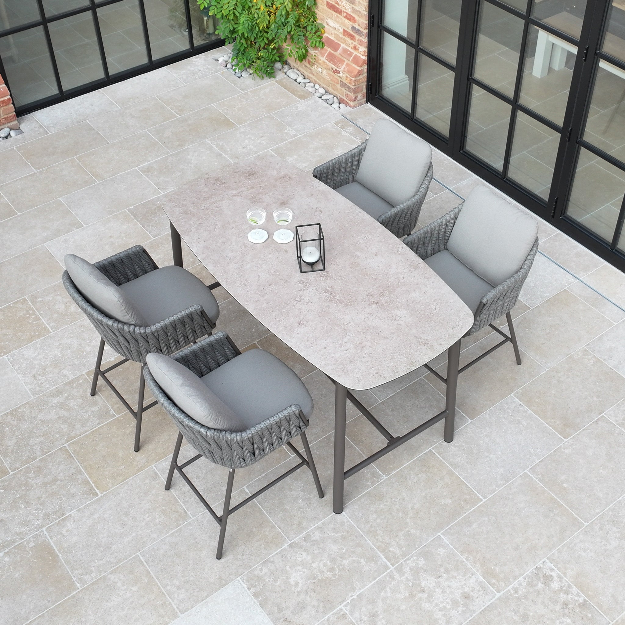 The Capri 4 Seat High Rectangular Dining Set in Stone Grey includes four cushioned chairs and a stylish table, making it ideal for outdoor dining on your terrace.