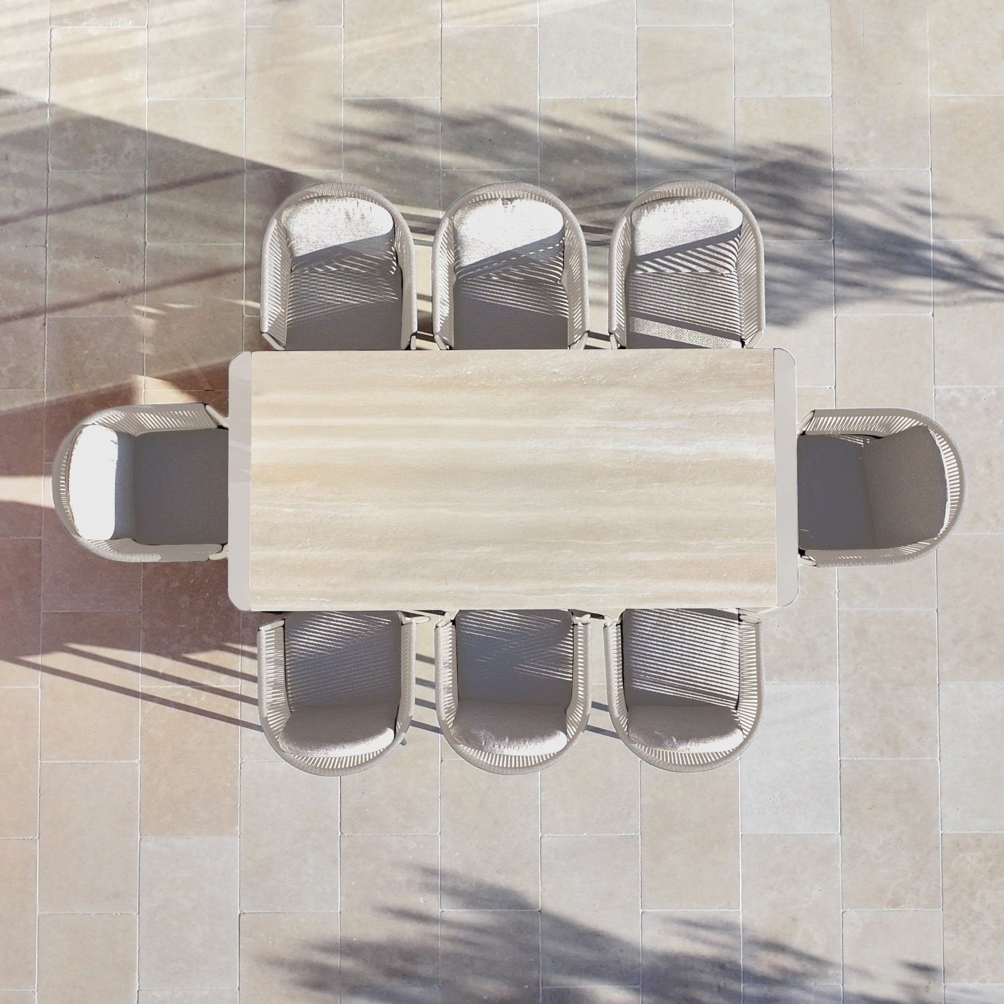 The Ravona 8 Seat Rope Extending Dining Set (207-277cm) in Latte, with chairs and a spacious table, is shown from above casting elegant shadows on a light-colored tiled floor.
