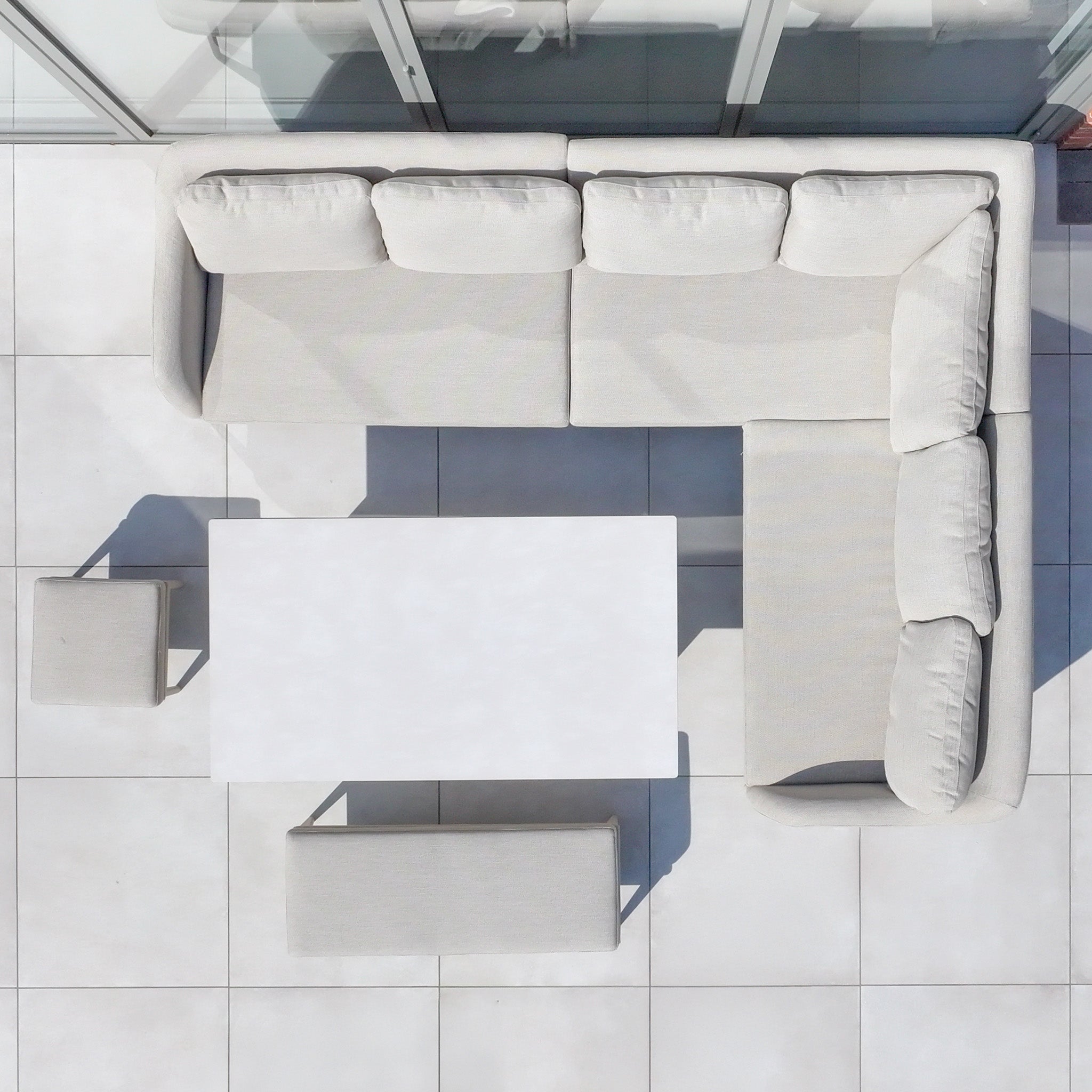 The Luna Outdoor Fabric Rectangular Corner Dining Set with Rising Table in Fawn (Left Hand) sits on white tiled flooring, viewed from above.