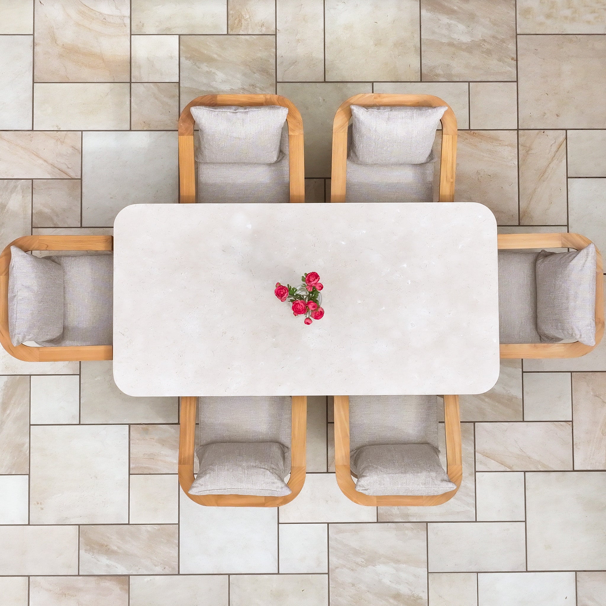 The Tivoli 6 Seat Dining Set with Marble Dining Table in Fawn is shown from above, featuring six chairs and a small bouquet of pink roses placed at the center of the rectangular table.