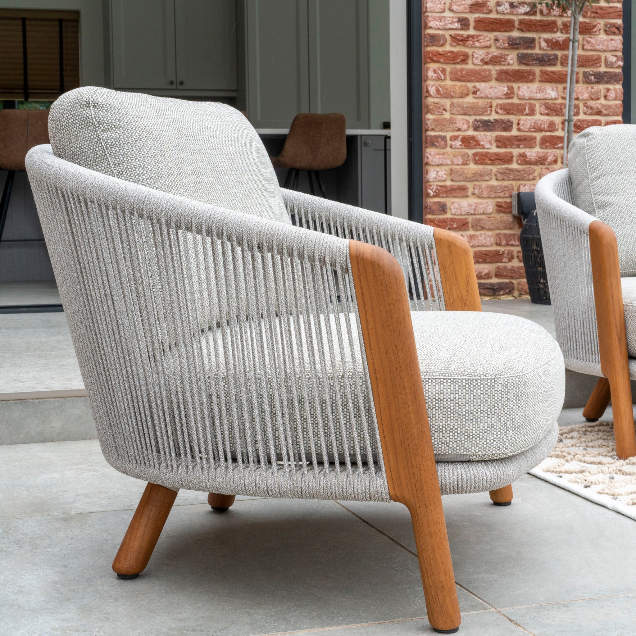 The Merano 2 Seat Sofa Set and Coffee Tables in Latte includes a cozy gray lounge chair with wooden armrests and legs, adorned with a hydrophobic olefin rope weave backrest design.