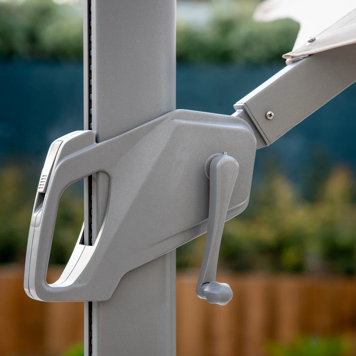 Close-up of the Ares 3m Square Cantilever Parasol's crank handle in charcoal against a blurred outdoor background, featuring a UV50+ canopy for superior sun protection and solar-powered LED lights.