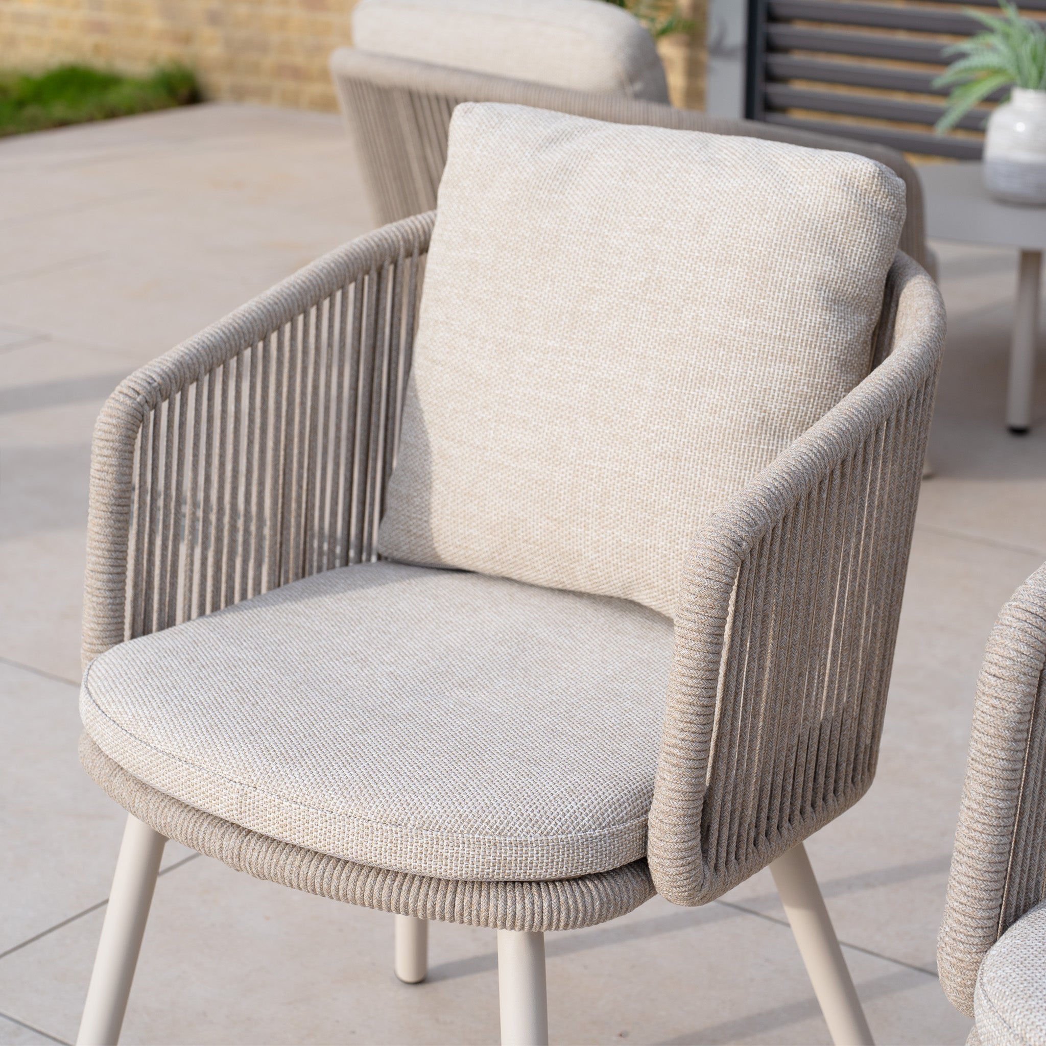 A set of two Dekota Dining Chairs in Fawn, featuring cushioned seats and backrests, perfect for a patio setting.