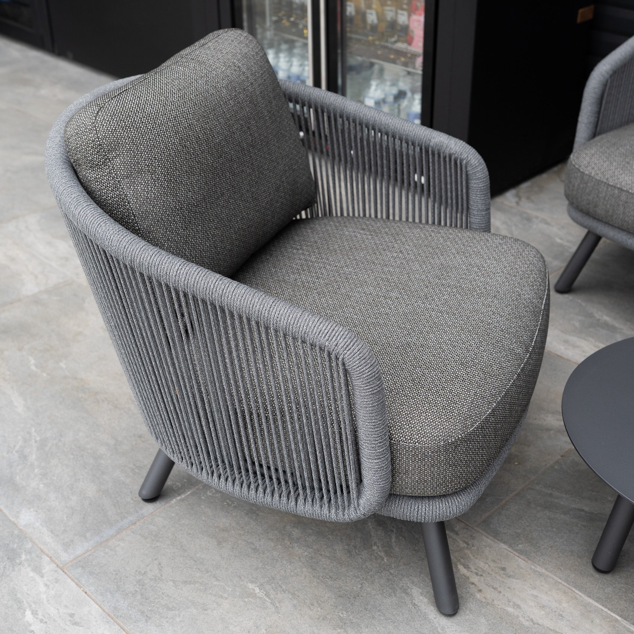 The Dekota 3 Seat Rope Sofa Set with Coffee Tables and Footstool in Charcoal features a rope-wrapped frame and plush olefin cushions, adding outdoor luxury to your space.