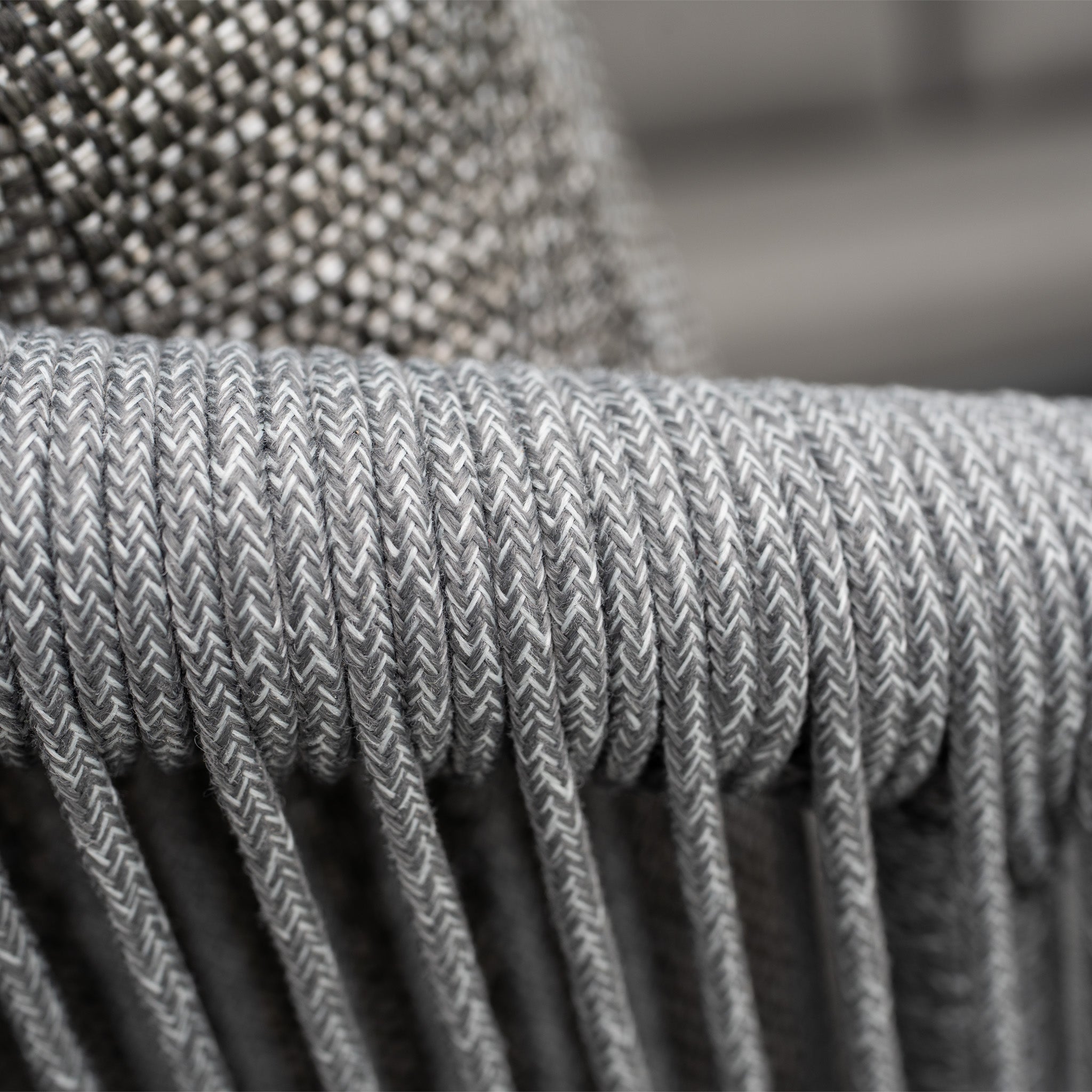 Close-up of tightly woven grey rope on the Dekota 3 Seat Rope Sofa Set with Coffee Tables and Footstool in Charcoal, set against a textured olefin fabric background that enhances outdoor style.