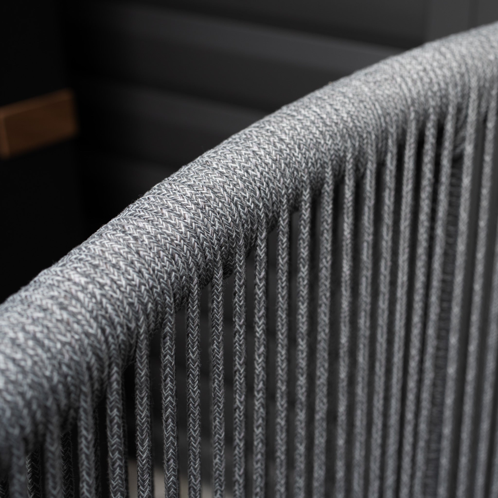 Close-up of the Dekota 3 Seat Rope Sofa Set in Charcoal, showcasing a gray woven backrest with vertical threading and a modern design, plus a powder-coated aluminium frame for luxurious outdoor durability.