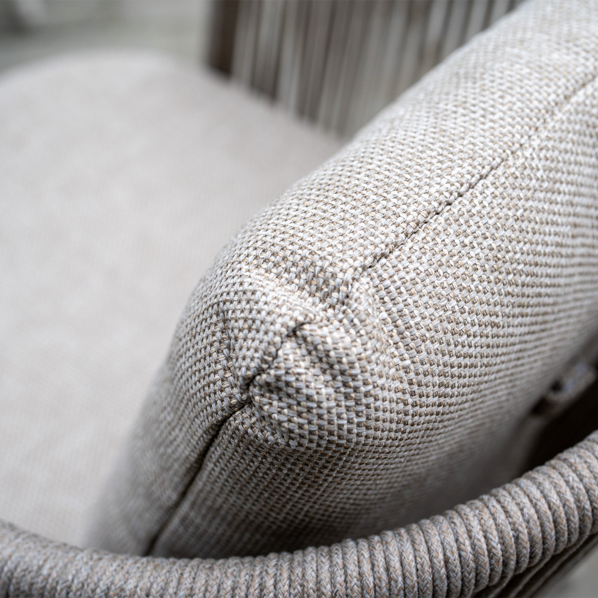 Close-up of a textured, neutral-colored woven pillow on outdoor furniture from the Dekota 4 Seat Round Rope Dining Set with Albatross Table in Fawn.