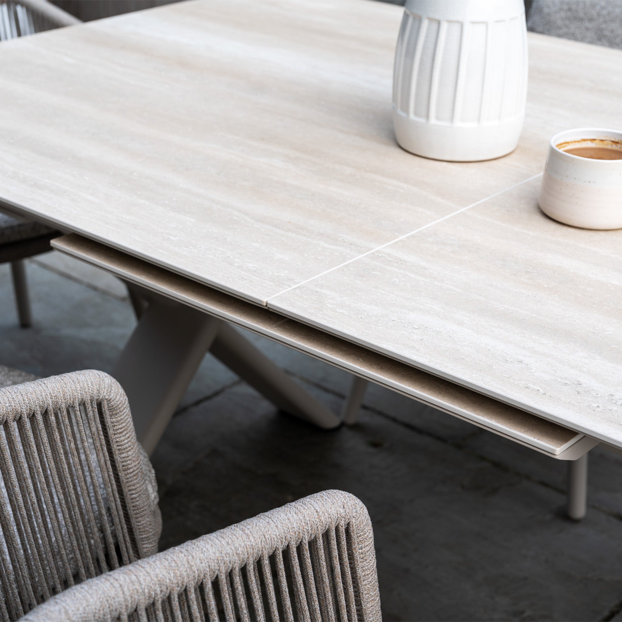 The Dekota 6 Seat Rope Dining Set with Albatross Extending Table in Fawn features woven chairs and a spacious table, creating an inviting outdoor dining space perfect for gatherings.