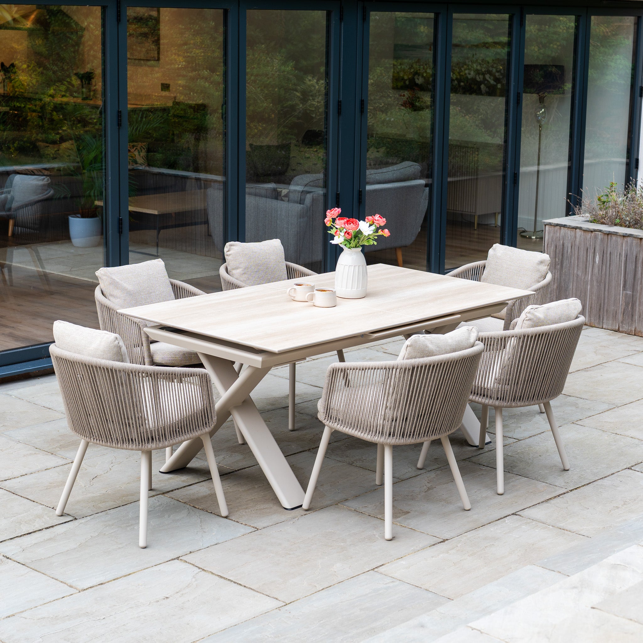 The Dekota 6 Seat Rope Dining Set with Albatross Extending Table in Fawn features cushioned chairs, creating a stylish and comfortable dining space for your patio.