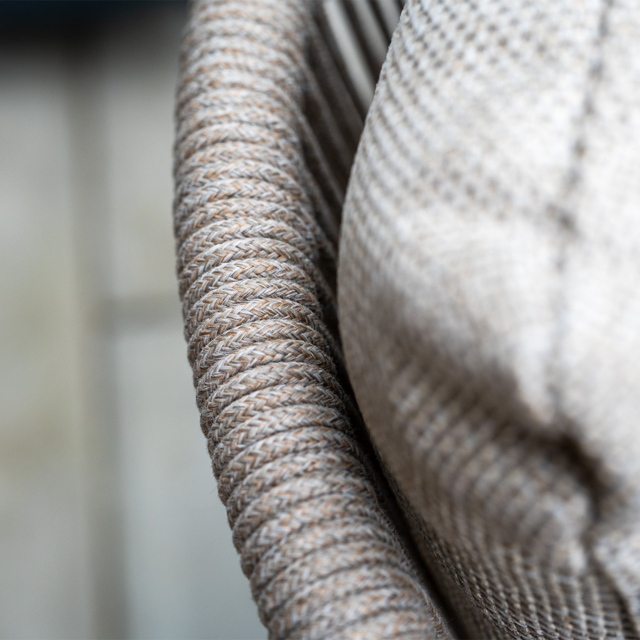 Close-up of a textured beige cushion on a woven chair, part of the Dekota 8 Seat Oval Rope Dining Set with Albatross Extending Table in Fawn, with a blurred wooden floor in the background.