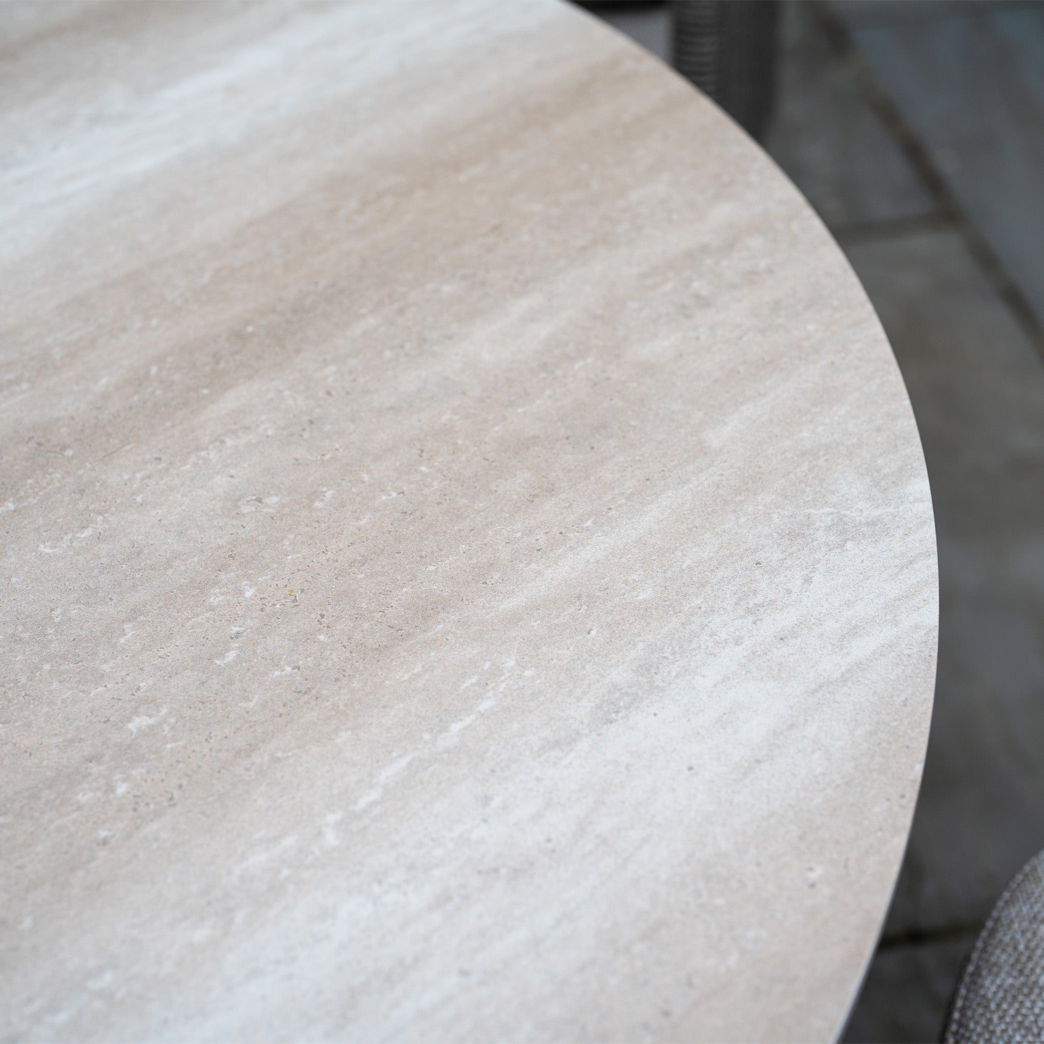 Close-up of the Dekota 8 Seat Oval Rope Dining Set with Albatross Extending Table in Fawn, showing its light tan, textured stone tabletop with swirling patterns and dark speckles—ideal for elegant outdoor dining.