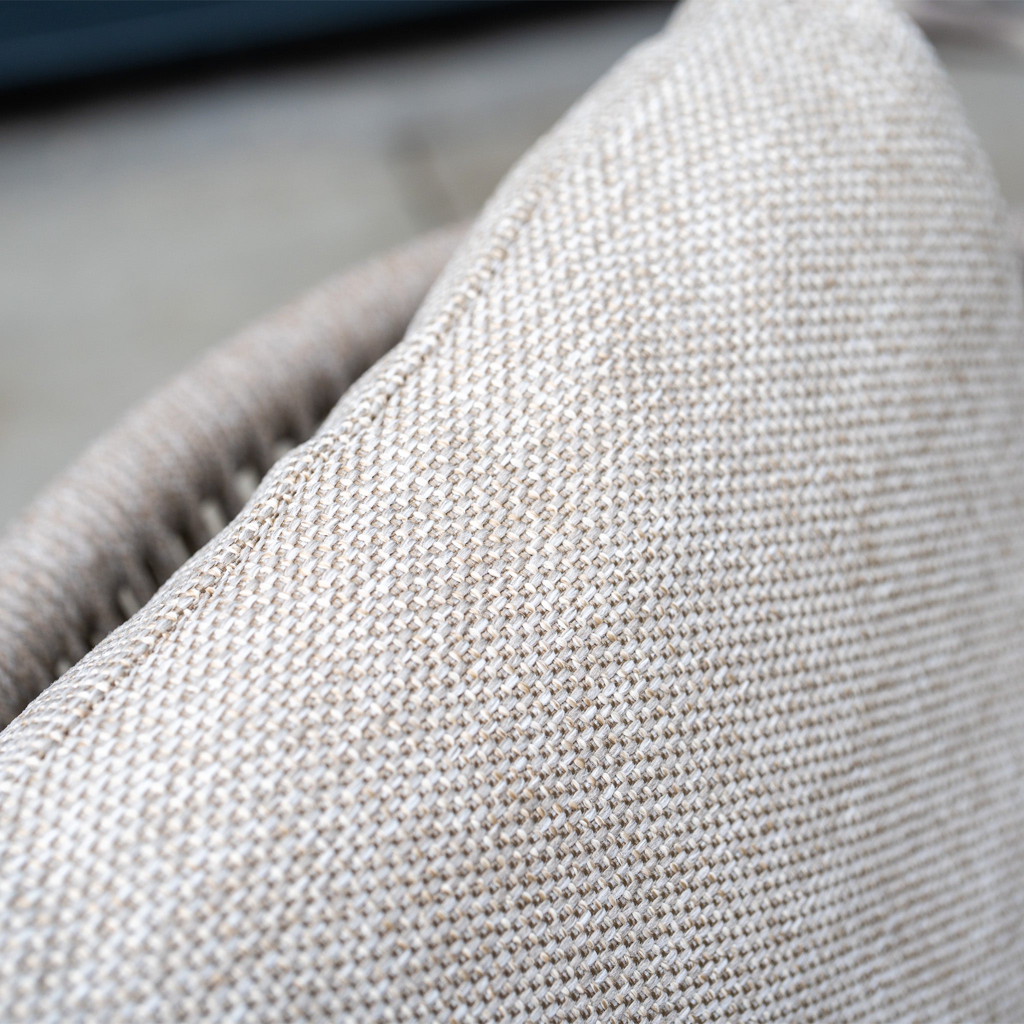 Close-up of a textured beige fabric cushion on the Dekota 8 Seat Oval Rope Dining Set with Albatross Extending Table in Fawn, with a blurred background for an inviting look.